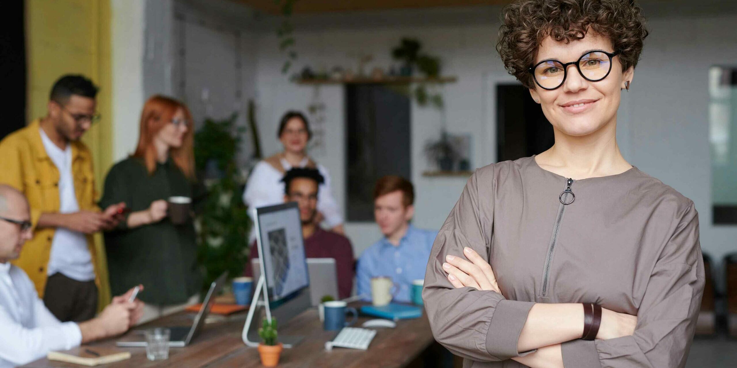 Successful woman CMO with her arms crossed in front of her team