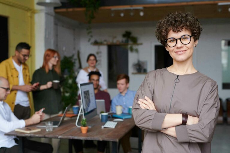 Successful woman CMO with her arms crossed in front of her team