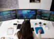 woman data scientist sitting at a computer with three screens of data